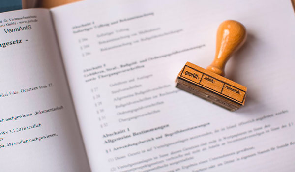 Rubber stamp resting on an open book with German text and numbered sections.